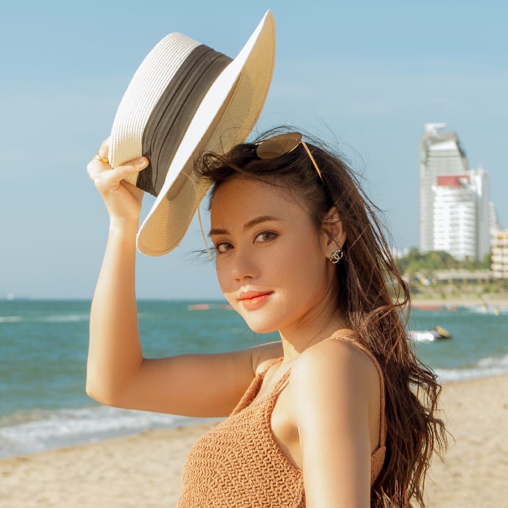 a woman tipping her hat on the beach