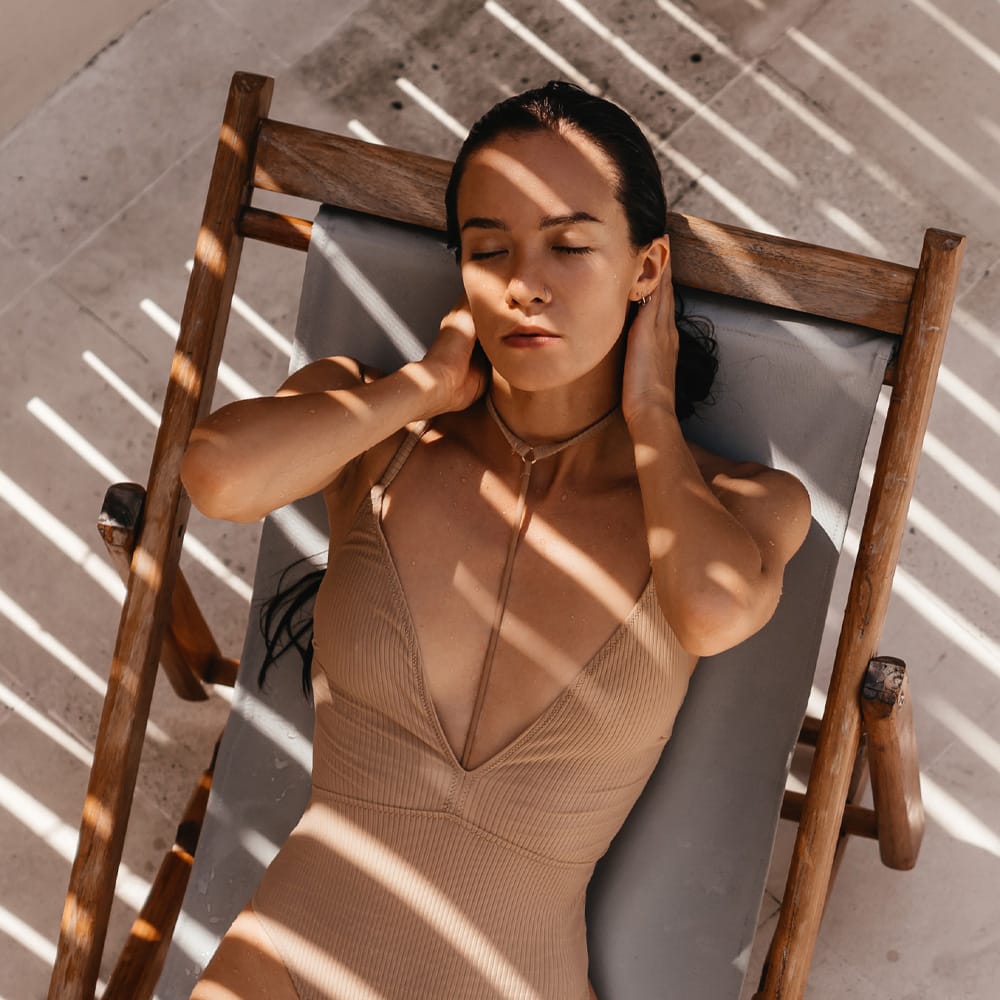 a woman sitting on a wooden chair in the shade