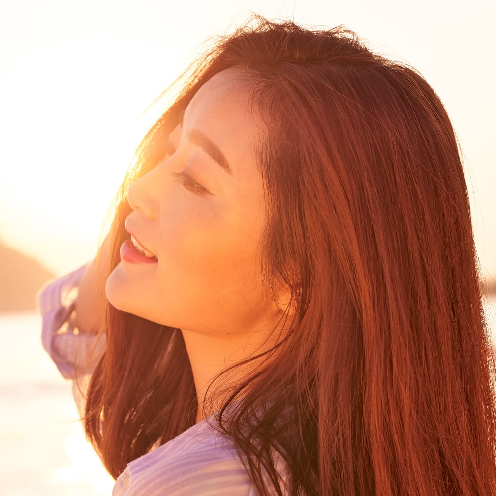 A woman smiling as the sun shines behind her